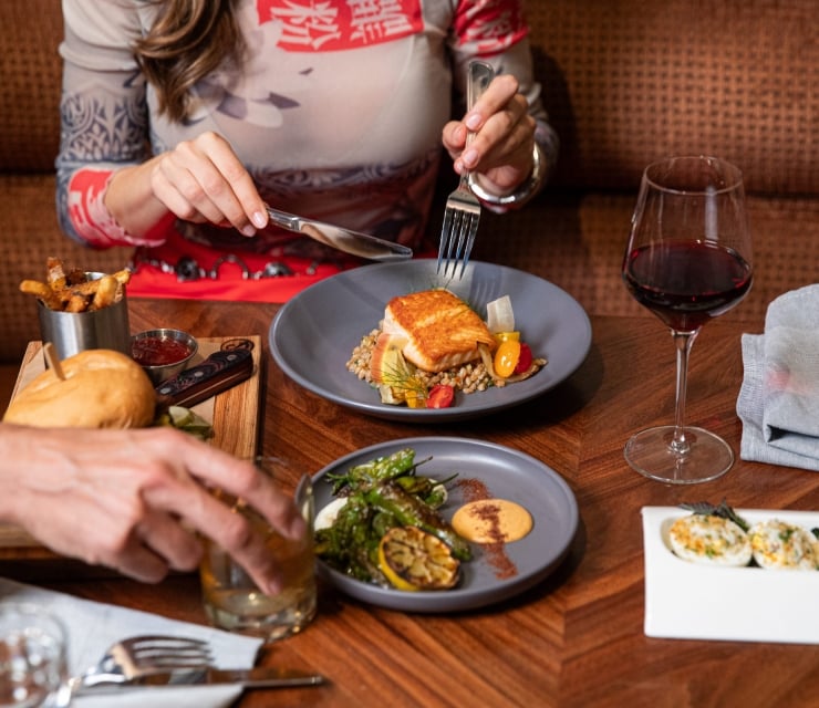 A couple sharing a variety of dishes from seared fish on farro, devilled eggs and a burger and fires