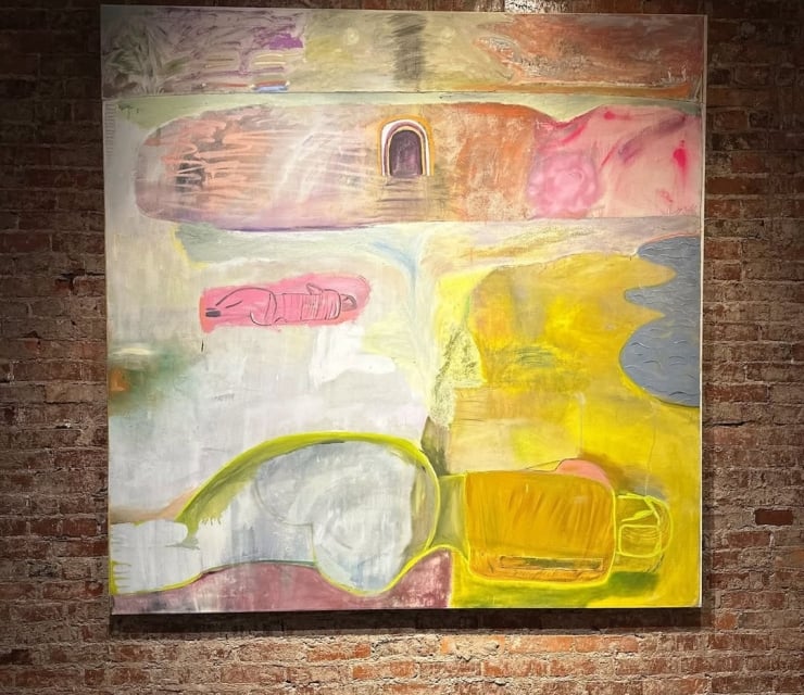 An abstract multimedia painting by John Paul Kesling hanging on an exposed brick gallery wall, featuring textured shades of yellow, pink, and muted grey with minimalist figures.
