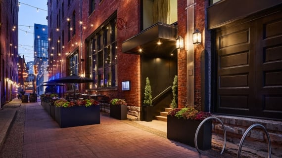 Bankers Alley entrance of The Untitled Nashville Hotel illuminated at dusk.